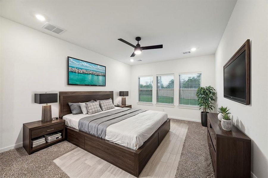 Retreat to this serene primary bedroom, where large windows bring in natural light and offer views of the private backyard. The neutral tones and spacious layout provide a calming atmosphere, perfect for unwinding after a long day.