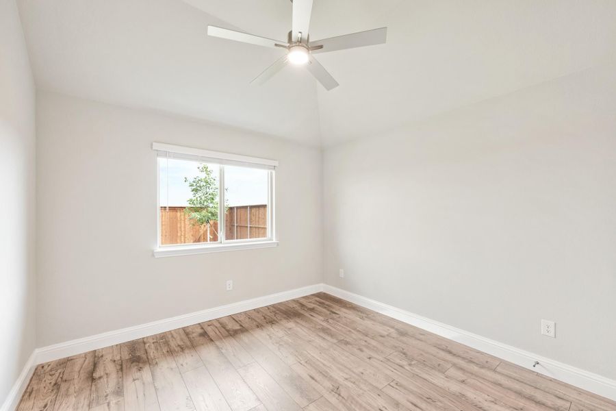 Empty bedroom with light wood floors, ceiling fan, and single window with backyard view Empty bedroom with light wood floors, ceiling fan, and single window with backyard view