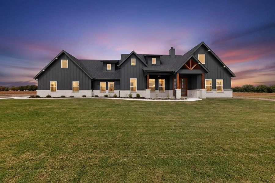 Modern farmhouse style home featuring board and batten siding, a front lawn, and a porch