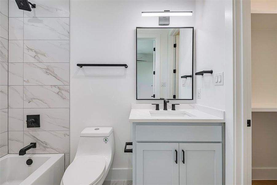 Full bathroom with vanity, tiled shower / bath combo, and toilet