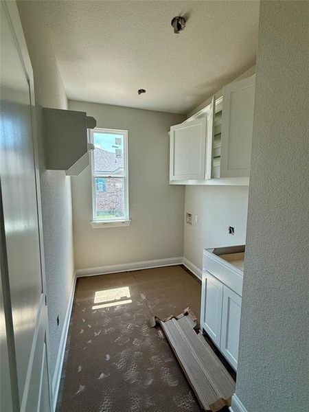 Washroom featuring washer hookup, a textured ceiling, a textured wall, and cabinet space Washroom featuring washer hookup, a textured ceiling, a textured wall, and cabinet space