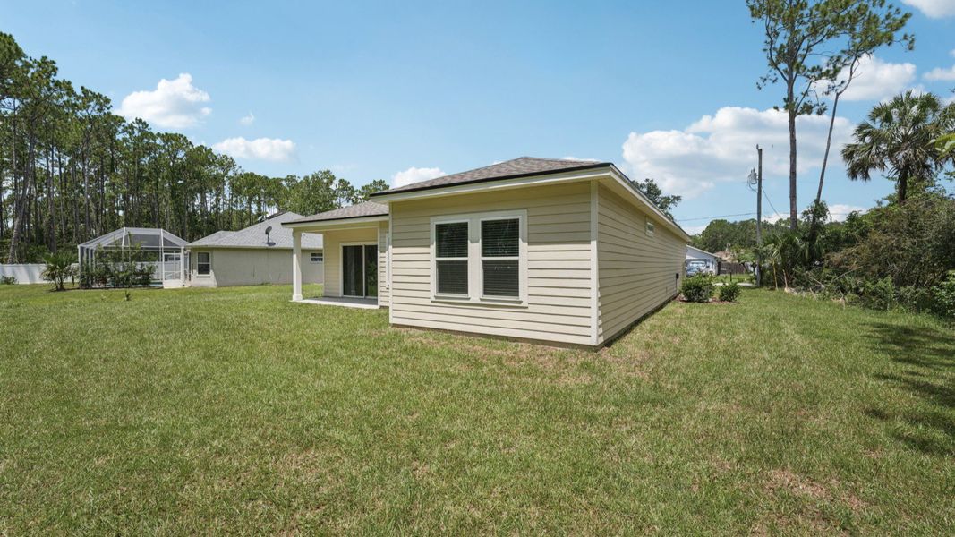Luxurious covered patio enhances this Palm Coast home's tranquil and expansive backyard.