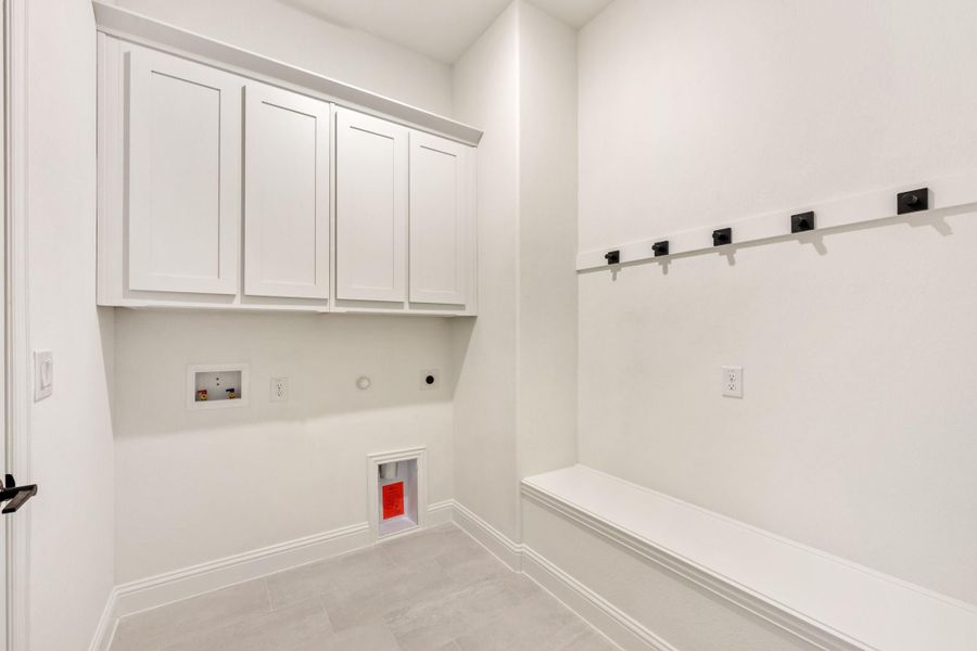 Mudroom with white upper cabinets, built-in bench, and black wall hooks for coats and bags Mudroom with white upper cabinets, built-in bench, and black wall hooks for coats and bags