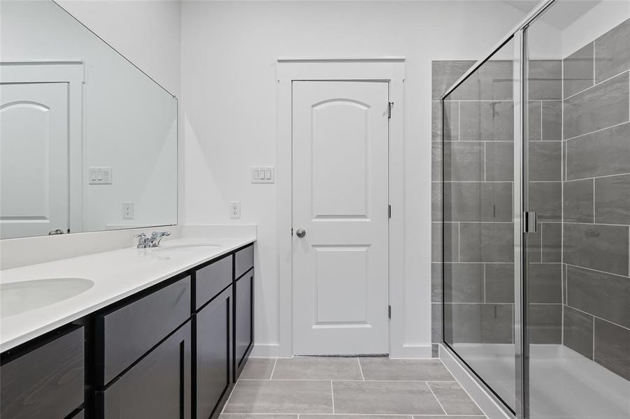 Bathroom featuring a stall shower, double vanity, and light tile patterned flooring Bathroom featuring a stall shower, double vanity, and light tile patterned flooring