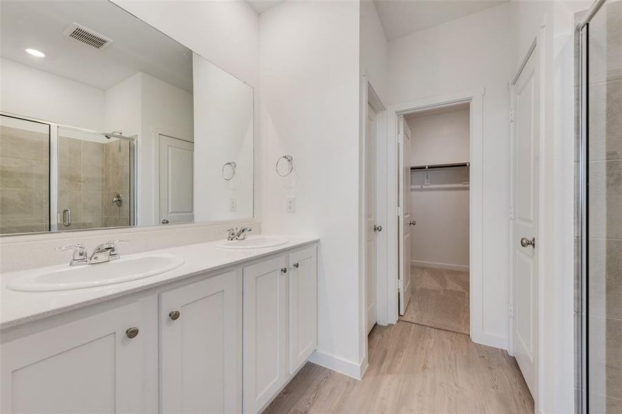 Bathroom with hardwood / wood-style flooring, a shower with door, and vanity