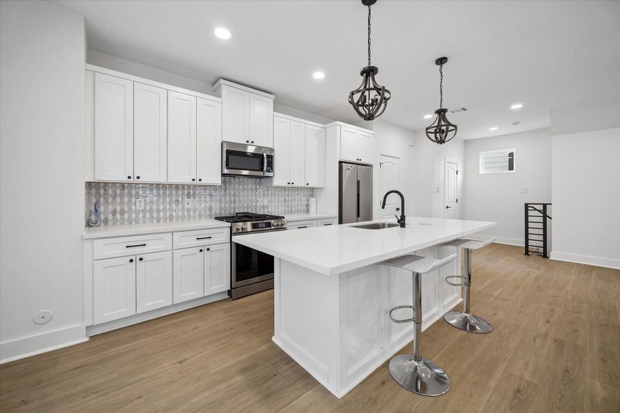 Quartz counters leave real prep space on the perimeter and the island both. Two stools tuck under the overhang for quick breakfasts. Quartz counters leave real prep space on the perimeter and the island both. Two stools tuck under the overhang for quick breakfasts.