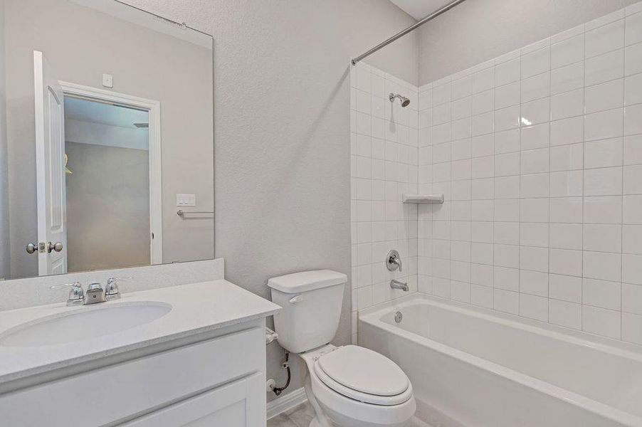 Bathroom with bathing tub / shower combination, vanity, and a textured wall Bathroom with bathing tub / shower combination, vanity, and a textured wall