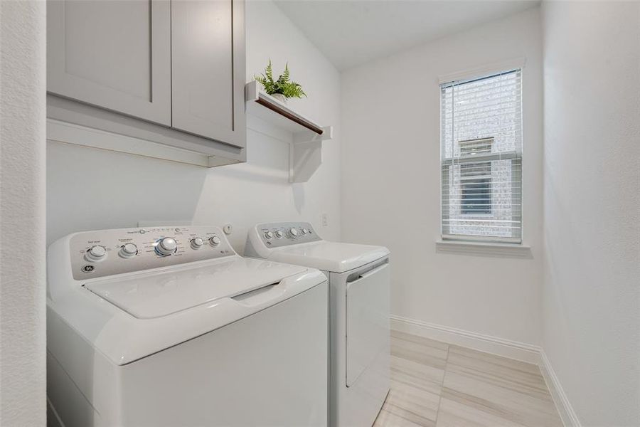 Laundry area with cabinets, independent washer and dryer, and light tile patterned floors