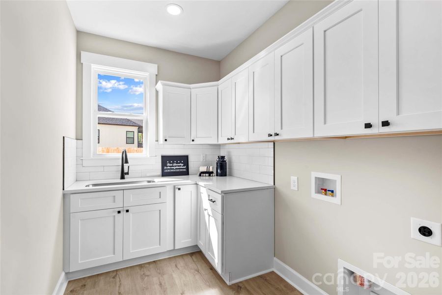 Laundry room is large with lots of cabinets & sink.