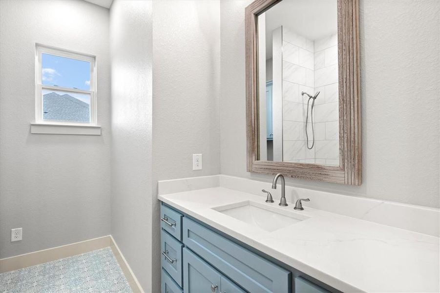 Full bathroom with vanity, a textured wall, and a tile shower Full bathroom with vanity, a textured wall, and a tile shower