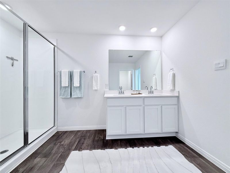 Bathroom with double vanity, a shower stall, and dark wood-style flooring Bathroom with double vanity, a shower stall, and dark wood-style flooring