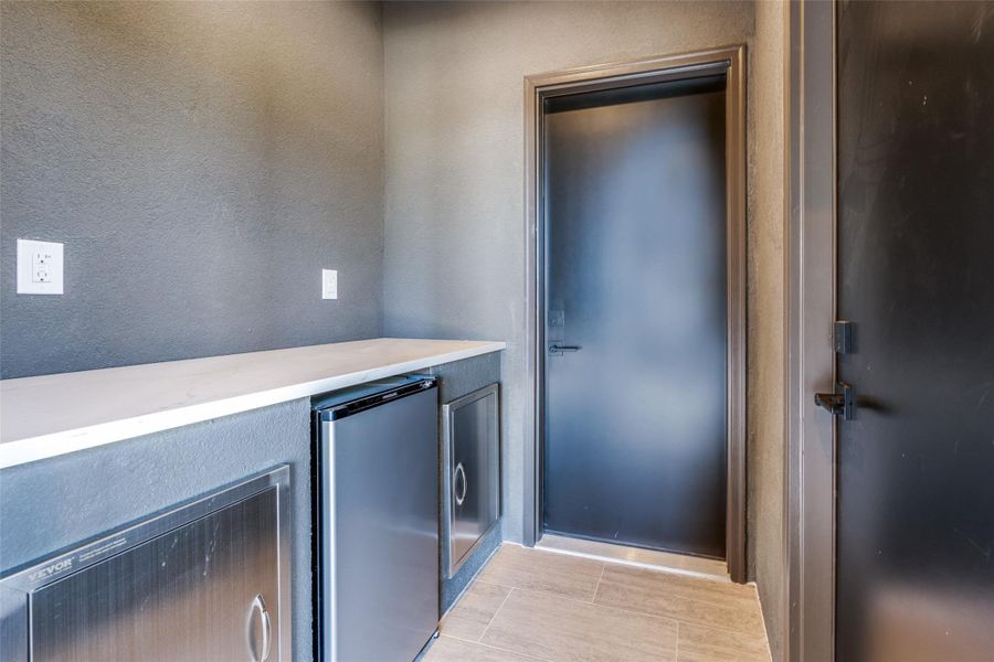 Bar featuring stainless steel fridge and a textured wall