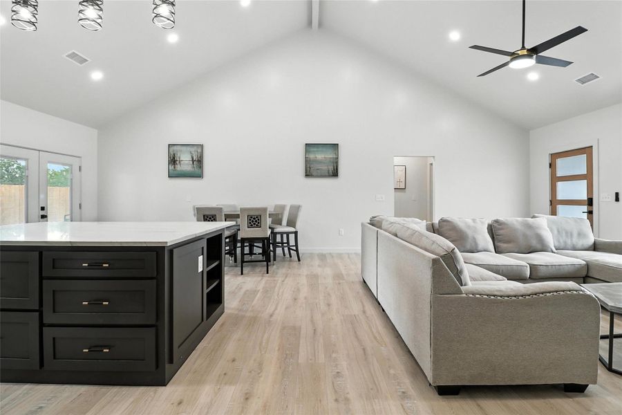 Living area featuring french doors, light wood finished floors, recessed lighting, high vaulted ceiling, and beamed ceiling