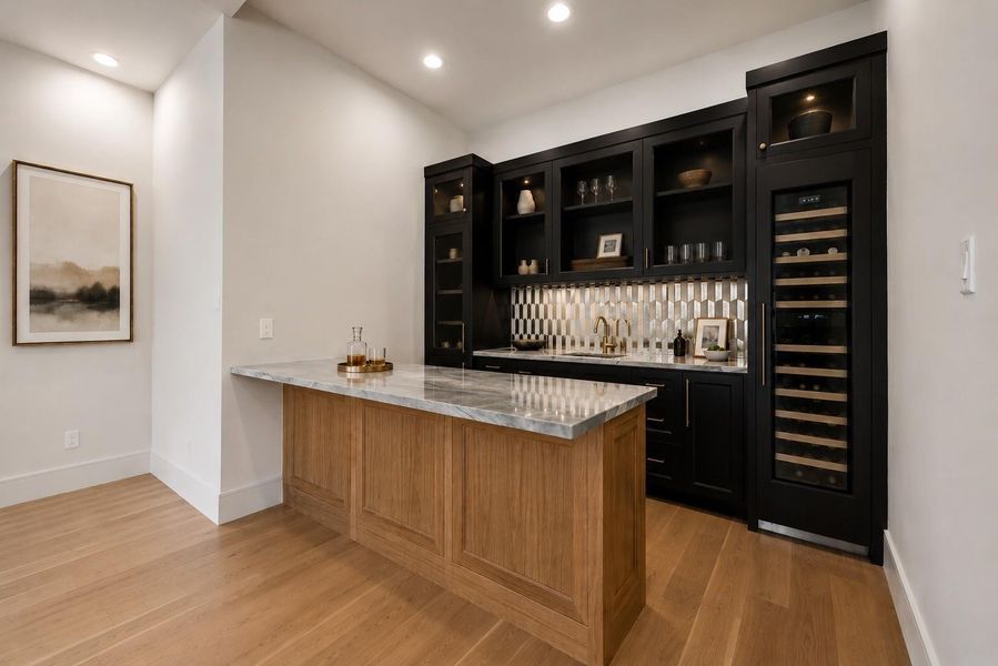 Entertain with ease in a dedicated wet bar featuring custom cabinetry, a built in wine refrigerator, prep sink, and expansive serving peninsula. Thoughtfully positioned just off the main living spaces, it creates a seamless destination for hosting while adding both style and everyday convenience. **Virtually staged**