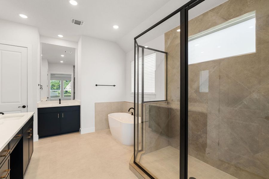 A primary bathroom featuring a freestanding tub and a spacious walk-in shower with tiled walls.