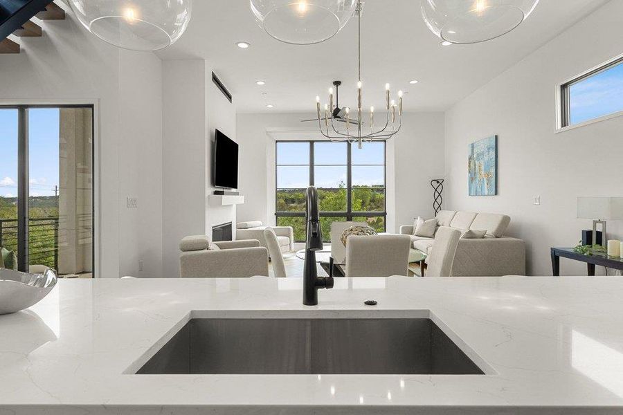 Kitchen island featuring a single-basin undermount sink with a black faucet, complemented by white countertops