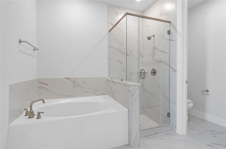 Indulge in relaxation within this spa-inspired primary bathroom, offering both a quick shower and a tranquil soaking experience. The walk-in shower is glass enclosed with modern tile walls and brushed nickel finishes.