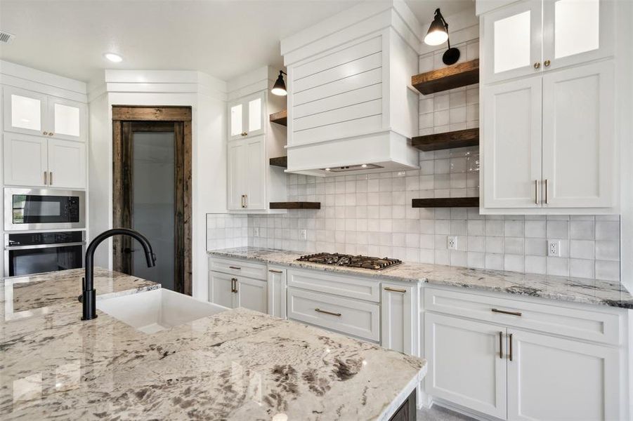 Kitchen with sink, appliances with stainless steel finishes, backsplash, and white cabinetry