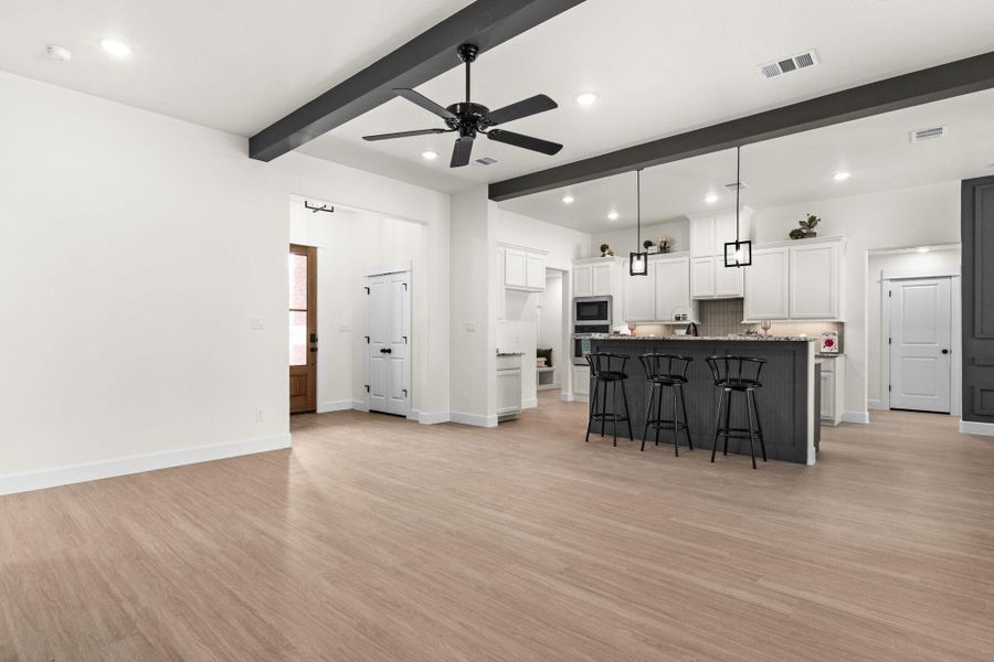 Kitchen with a breakfast bar area, light wood-type flooring, a ceiling fan, open floor plan, and beam ceiling