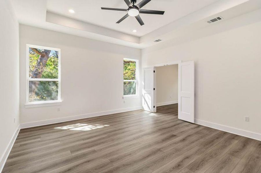 Primary Bedroom featuring a tray ceiling, ceiling fan, dark wood finished floors, and recessed lighting