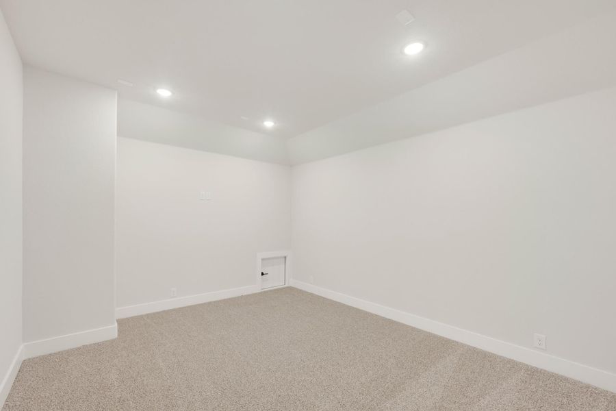 Empty basement room with white walls, beige carpet, and recessed ceiling lights