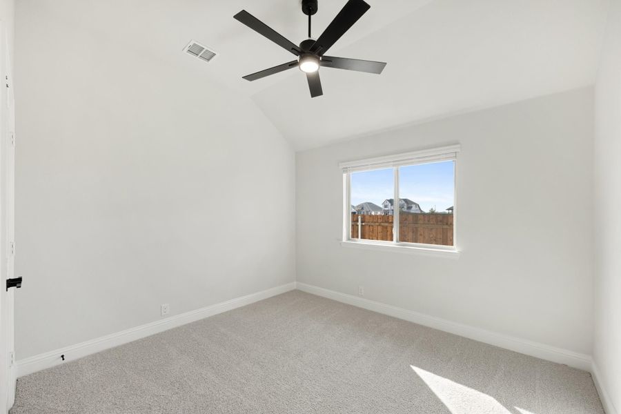 Empty bedroom with vaulted ceiling, black ceiling fan, carpet flooring, and single window