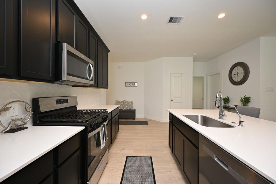 Sleek cabinetry, stainless steel appliances, and a spacious island with a sink. The open layout is complimented by light wood flooring and recessed lighting, creating a bright and inviting space. Sleek cabinetry, stainless steel appliances, and a spacious island with a sink. The open layout is complimented by light wood flooring and recessed lighting, creating a bright and inviting space.