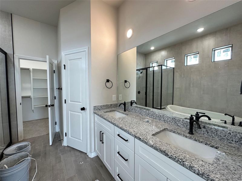 Bathroom with a stall shower, a spacious closet, double vanity, dark wood-style flooring, and a tub
