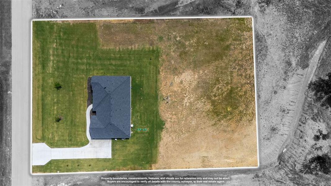 Aerial view showcasing a detached property with a dark shingle roof and a concrete driveway