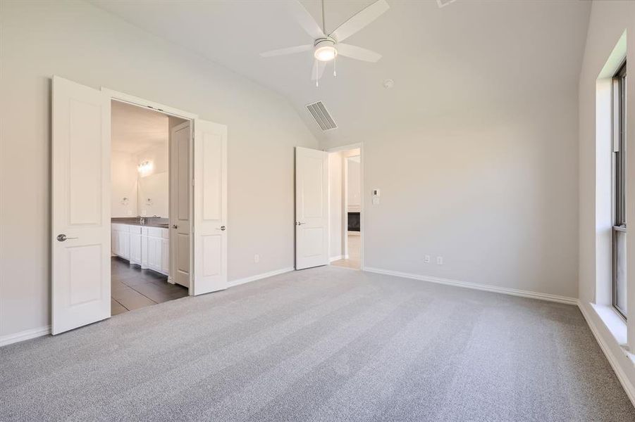 Unfurnished bedroom with lofted ceiling, ensuite bath, carpet, and ceiling fan