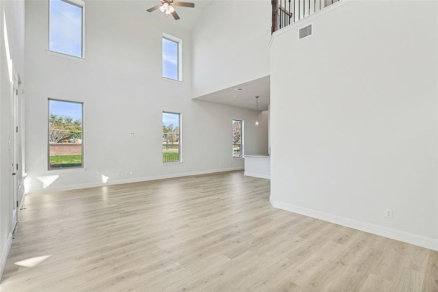 Unfurnished living room with a high ceiling, light hardwood / wood-style floors, and ceiling fan