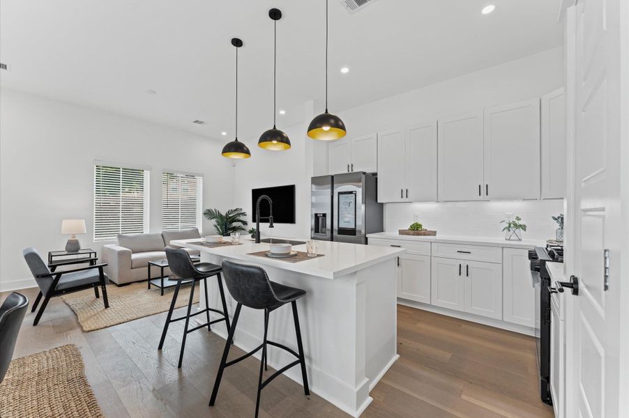 This centrally positioned kitchen island serves as a stylish anchor within the open-concept layout, offering clear sightlines to the dining area, living space, and the front yard. Its placement encourages seamless interaction, whether prepping meals or entertaining guests, while natural light pours in through the nearby windows. The island’s sleek design and functional surface make it a hub of activity, framed by elegant finishes tying together comfort and sophistication.