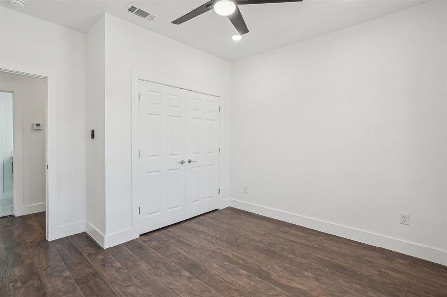 Front bedroom 1 with ceiling fan, a closet, and dark wood-type flooring