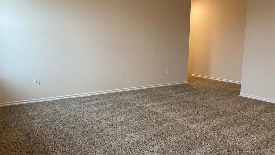 Empty room featuring dark colored carpet and baseboards