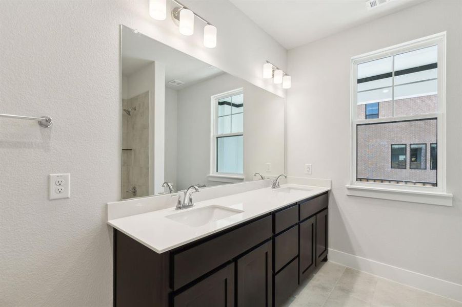 Secondary Bathroom featuring double vanity, baseboards, a shower, and a sink