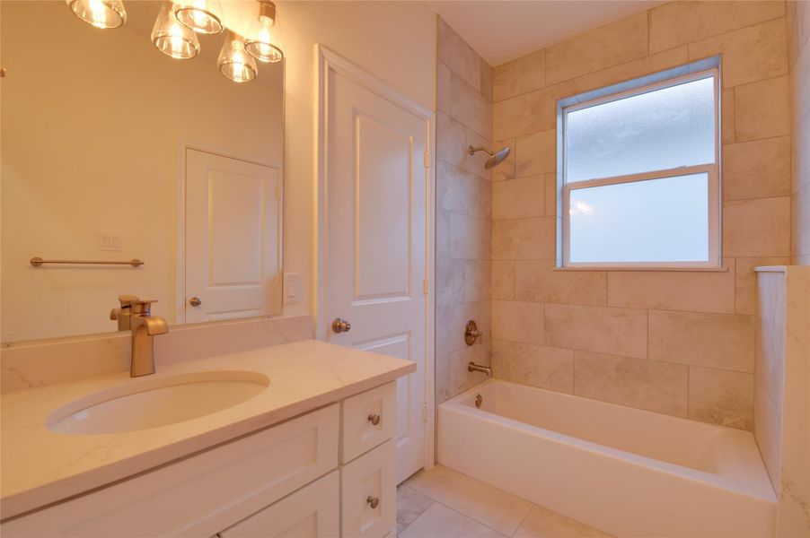 Stylish full bath with a quartz-topped vanity andchic gold fixtures. Oversized tile surrounds a deeptub/shower combo with a rainfall head, plus afrosted window for natural light and privacy.Convenient linen closet and fresh neutral finishes. Stylish full bath with a quartz-topped vanity andchic gold fixtures. Oversized tile surrounds a deeptub/shower combo with a rainfall head, plus afrosted window for natural light and privacy.Convenient linen closet and fresh neutral finishes.