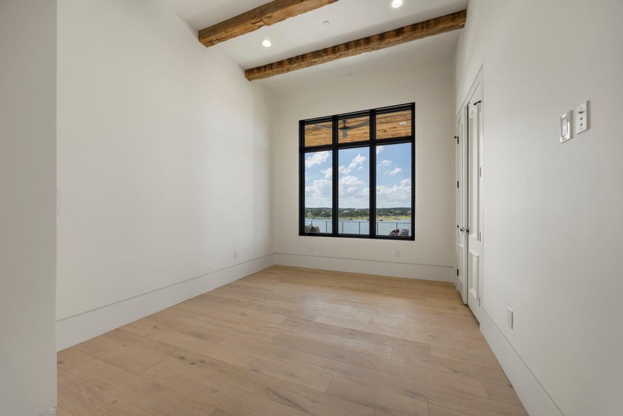 Exposed beams complement bright hardwood floors, framing a captivating water view through large windows. Exposed beams complement bright hardwood floors, framing a captivating water view through large windows.