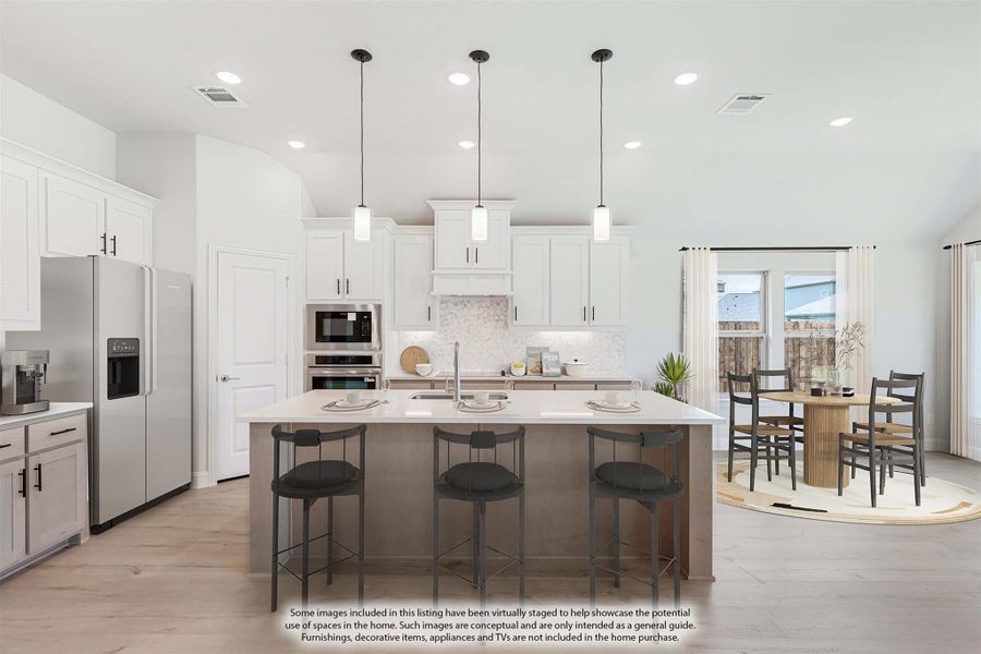 Open kitchen with white cabinets, large island with bar stools, stainless steel appliances, and adjacent dining area with hardwood floors