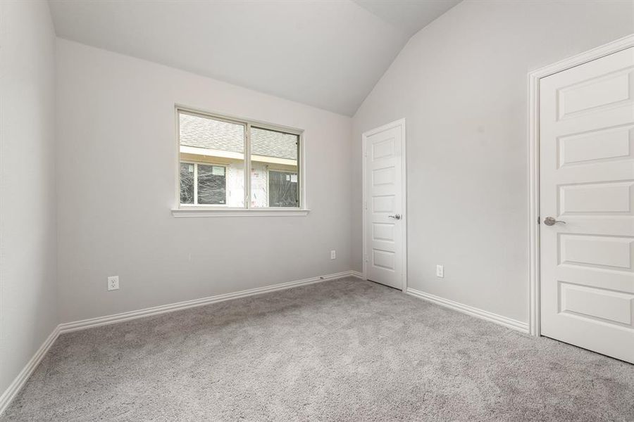 Unfurnished room featuring light carpet and lofted ceiling