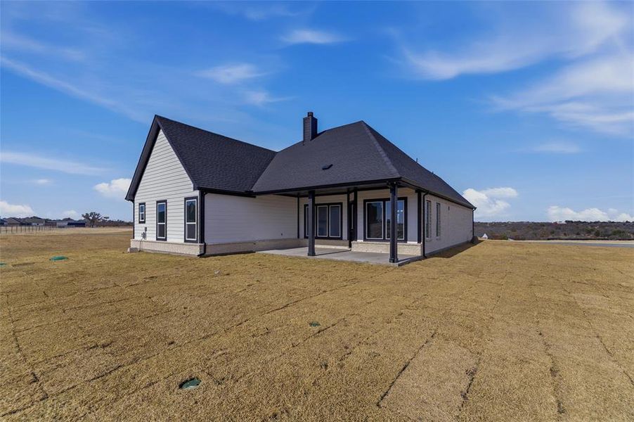 Rear view of property with a chimney, a yard, and a patio area
