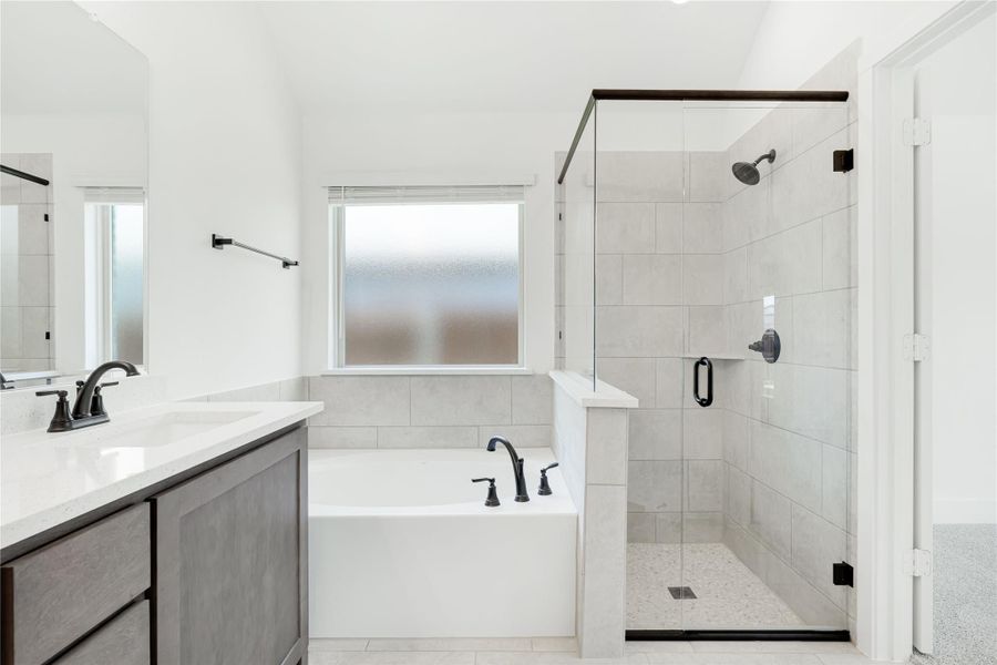 Master bathroom with soaking tub, glass-enclosed tile shower, and double vanity with dark fixtures Master bathroom with soaking tub, glass-enclosed tile shower, and double vanity with dark fixtures