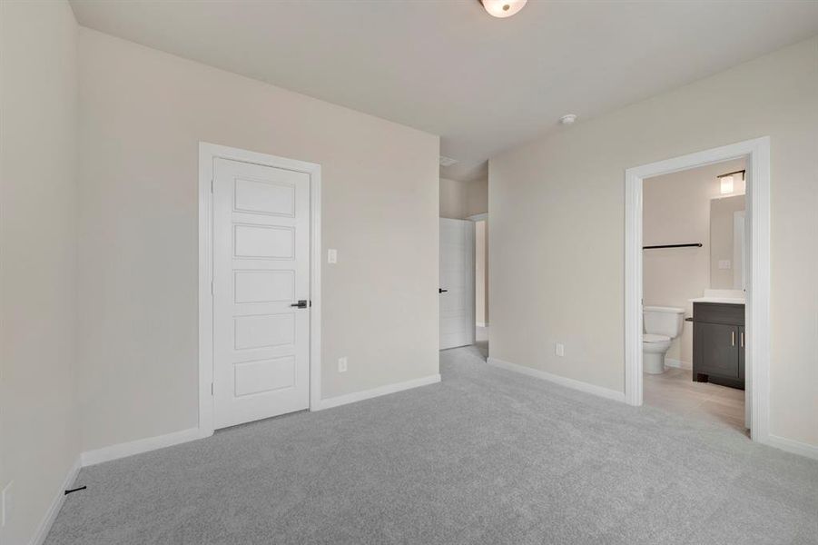 Unfurnished bedroom featuring light carpet and ensuite bathroom