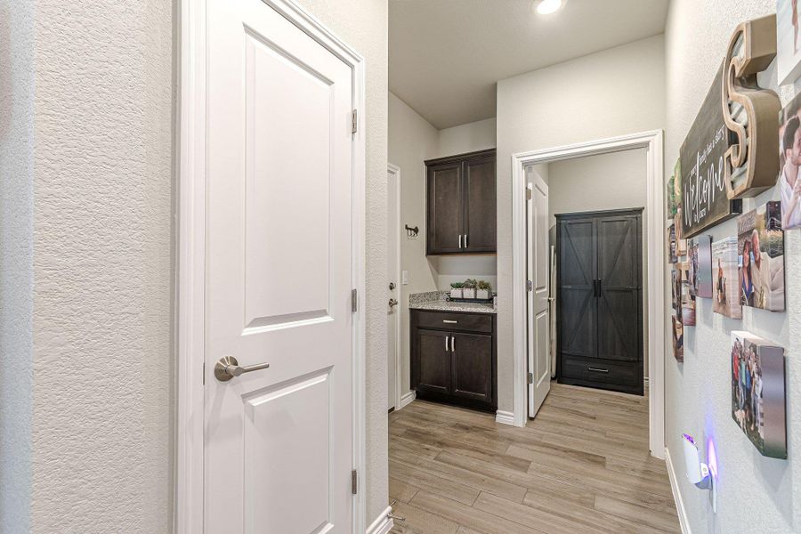 Laundry area featuring light wood-style floors, baseboards, a textured wall, and recessed lighting