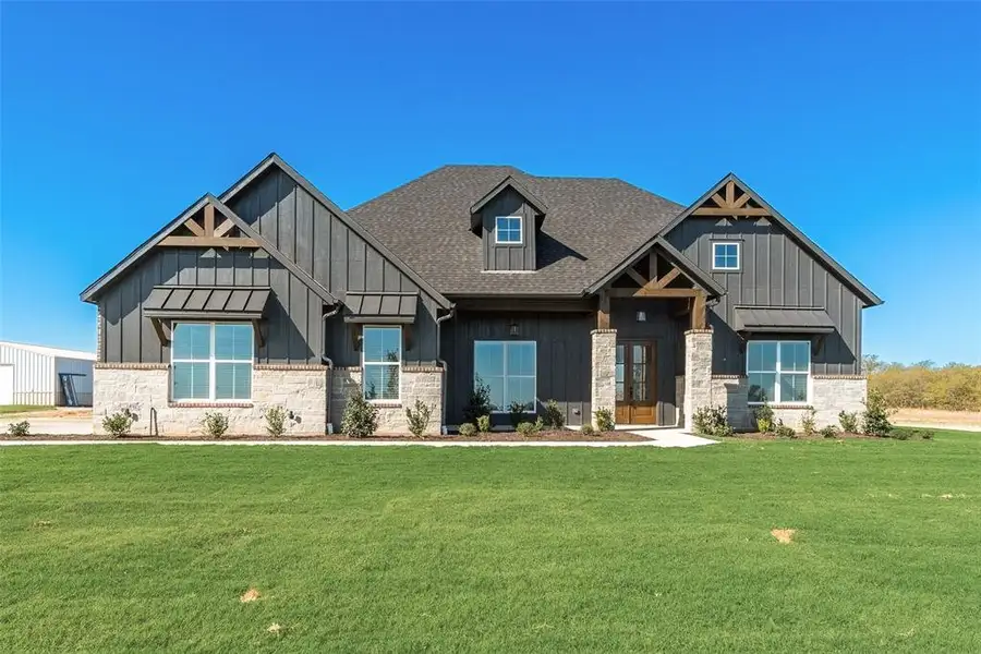 Modern farmhouse exterior featuring dark vertical siding and a light stone facade