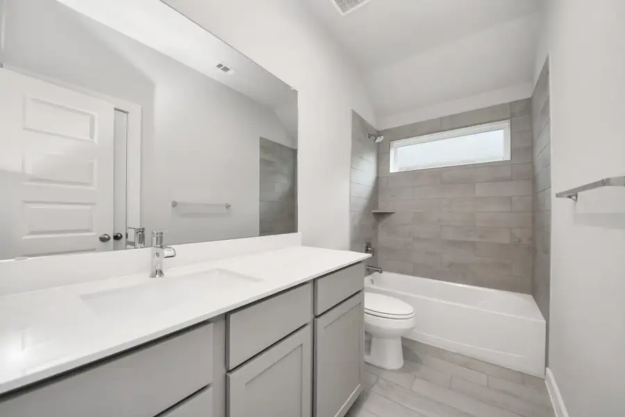 Secondary bath features tile flooring, bath/shower combo with tile surround, light stained wood cabinets, beautiful light countertop. Sample photo of completed home with similar floor plan. Actual colors and selections may vary. Secondary bath features tile flooring, bath/shower combo with tile surround, light stained wood cabinets, beautiful light countertop. Sample photo of completed home with similar floor plan. Actual colors and selections may vary.