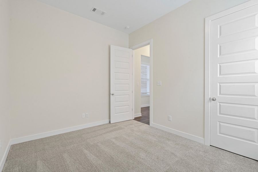 Neutral-toned room featuring light gray carpet flooring and white baseboards Neutral-toned room featuring light gray carpet flooring and white baseboards
