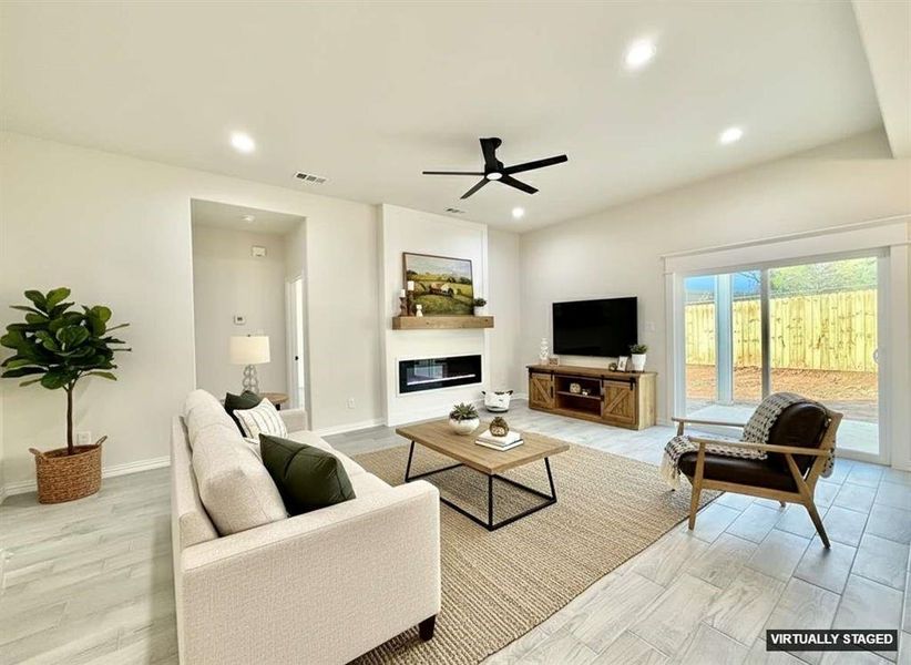 Living room with recessed lighting, a glass covered fireplace, light wood-style floors, and a ceiling fan Living room with recessed lighting, a glass covered fireplace, light wood-style floors, and a ceiling fan