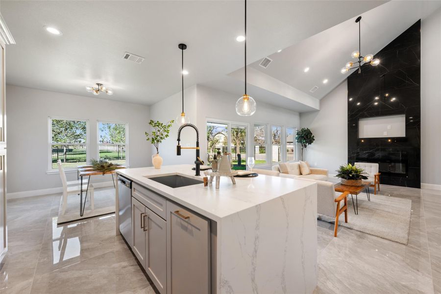 Kitchen featuring light marble finish flooring, decorative light fixtures, light stone countertops, a chandelier, and high vaulted ceiling
