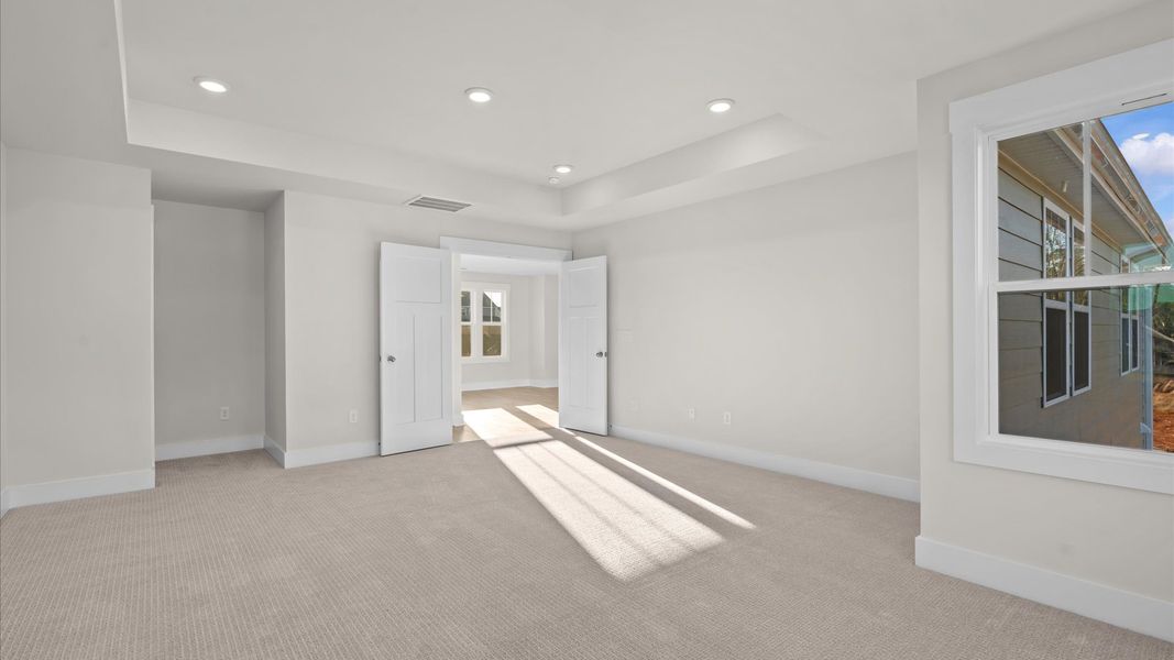 Elegant primary suite with tray ceiling, french doors, and walk-in closet in this top-notch home