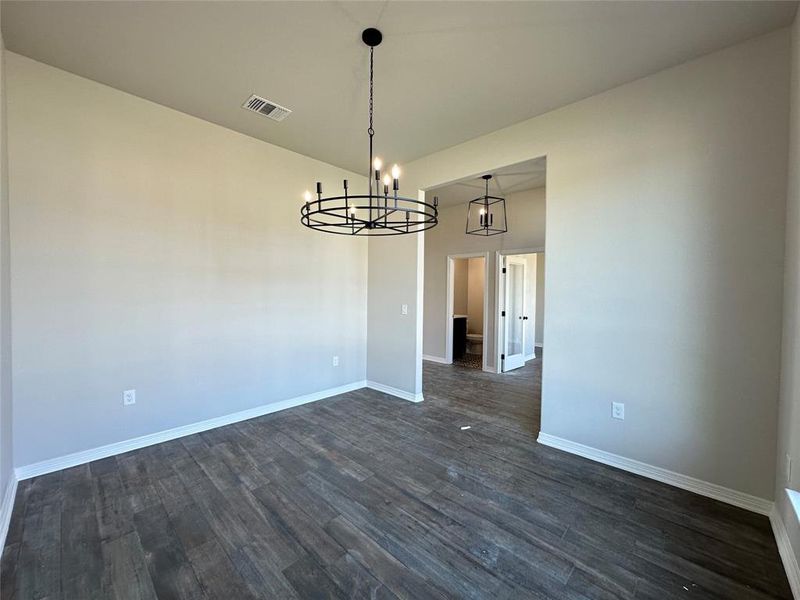 Unfurnished dining area featuring dark wood-style floors and a chandelier Unfurnished dining area featuring dark wood-style floors and a chandelier